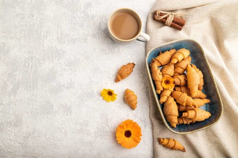 Homemade bagel roll with cup of coffee on a gray concrete background and linen textile. top view,