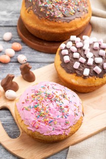 Homemade glazed and decorated easter pies with chocolate eggs and rabbits on a gray wooden