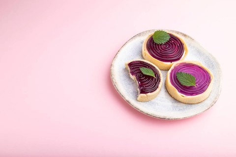Sweet tartlets with jelly and milk cream on a pastel pink background. Side view, copy space