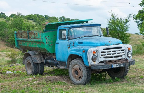 Weathered blue lorry on a rural meadow under a cloudy sky, ZIL-130, Soviet Russian vehicle
