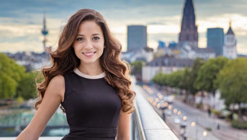 A woman in an evening dress smiles on a city bridge with twilight lights, AI generated, AI
