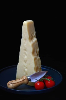 A piece of Parmesan cheese with cheese knife and tomatoes, Italy, Europe