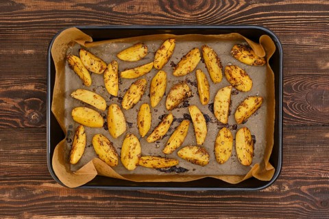 Top view of potato wedges baked in oven in baking tray