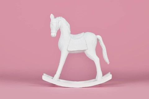 White wooden retro style rocking horse Christmas home decor object on pink background