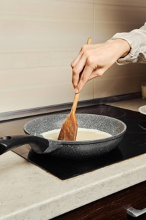 Unrecognizable woman miking scrambled eggs in a frying pan in her kitchen