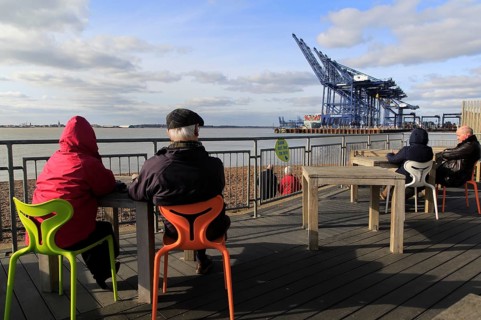 People sitting outside cafe viewing area for Port of Felixstowe, Suffolk, England, UK