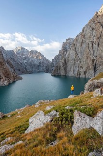 Tourist at the blue mountain lake between rocky steep mountain peaks, Kol Suu Lake, Sary Beles