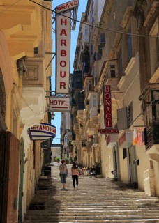 Steps climb hill of narrow street historic housing with traditional balconies in city centre of