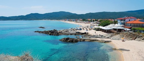 Wide coastal landscape with turquoise water and mountains in the background, lined with beaches,