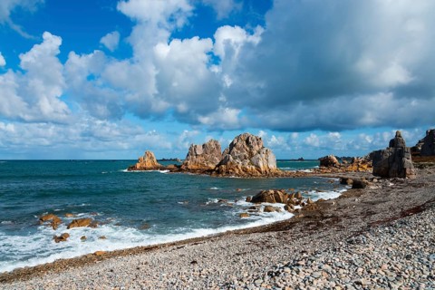Rocks and sea on a coastline under a dramatic sky with clouds and blue sky, Plage de Pors Scaff,