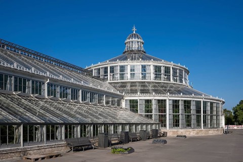 Large historic greenhouse, palm house with glass façade, blue sky, Botanical Garden or Botanisk