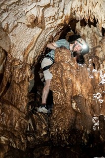 Young man with helmet and headlamp, tourist between stalactites and stalagmites in a stalactite