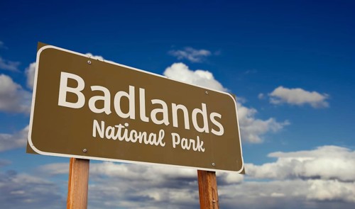 Badlands national park (south dakota) road sign against blue sky and clouds