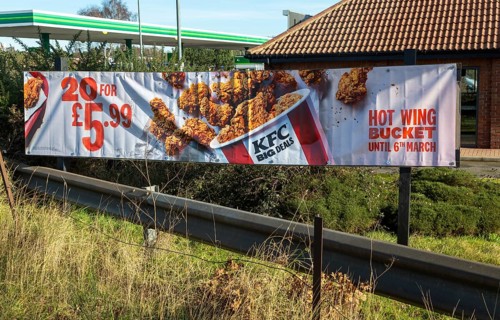 Banner sign advertising KFC Hot Bucket Wings, Kentucky Fried Chicken outlet, Martlesham, Suffolk,