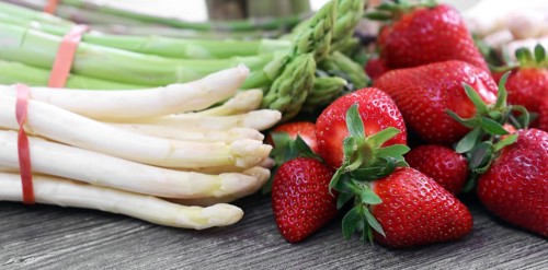 Green asparagus, white asparagus and fresh strawberries decorated on a rustic wooden table
