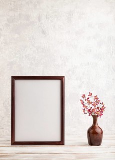 Wooden frame with purple barrenwort flowers in ceramic vase on gray concrete background. side view,