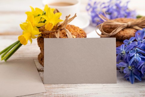 Gray paper business card mockup with oatmeal cookies with spring snowdrop flowers bluebells,