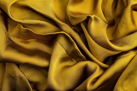 Fragment of yellow and green tissue. Side view, synthetic textile background and texture. wave