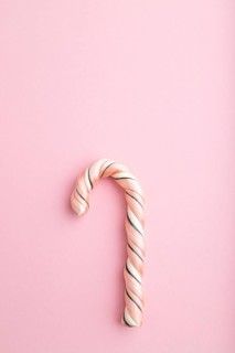 Single cane candy on pink pastel background. copy space, top view, flat lay