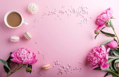 Pink peony flowers and a cup of coffee on a pink pastel background. Morninig, spring, fashion