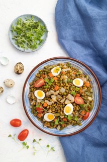 Mung bean porridge with quail eggs, tomatoes and microgreen sprouts on a white concrete background