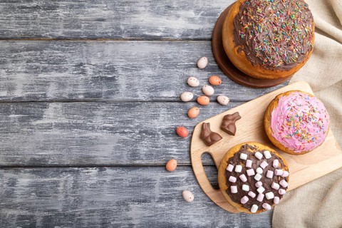 Homemade glazed and decorated easter pies with chocolate eggs and rabbits on a gray wooden