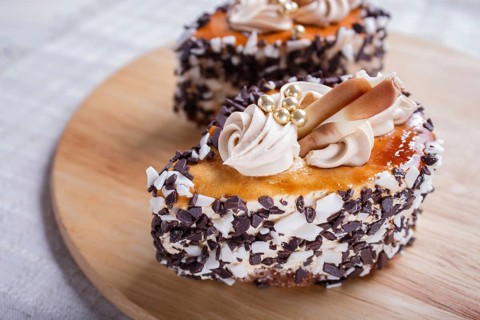 Cakes with chocolate chips and cream decorations on wooden board on white background. selective