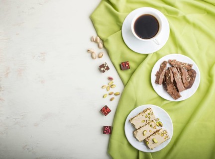 Traditional arabic sweets sesame halva with chocolate and pistachio and a cup of coffee on a white