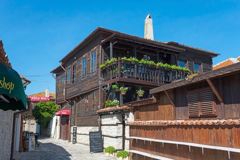 Wooden house with flower-planted balconies and various signs, in a cobblestone alley, Black Sea,