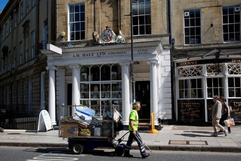 Street cleaner pulling a rubbish collection cart in Argyle Street, Bath, Somerset, England, United