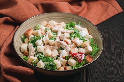 Fresh traditional Caesar salad, with chicken, on a wooden background, Top view, toned, horizontal