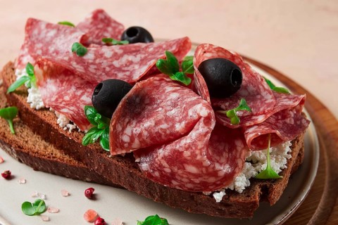 Sandwich, grain bread, with cream cheese and salami, black olives, micro-greens, top view,