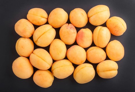 Apricots on black background, top view, flat lay