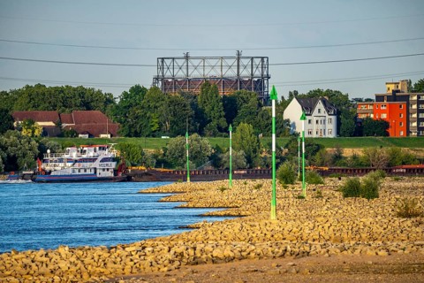 Cargo ship at low water on the Rhine near Duisburg-Homberg, view of Duisburg-Laar, houses on