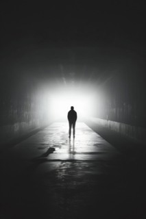 Silhouette of a man standing in a tunnel, light at the end of the tunnel, symbolic image for