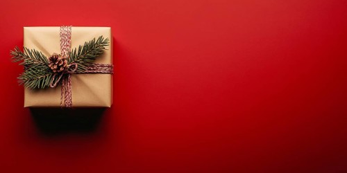 Banner with small Christmas gift box wrapped in graft paper on red background with copy space.