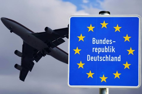 Symbolic image of the asylum debate: A plane taking off next to a border sign of the Federal