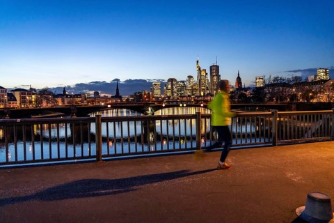 Skyline of the city centre of Frankfurt am Main, jogger on the raft bridge, dusk, river Main,