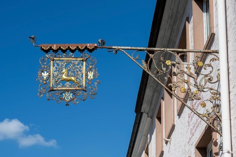 Nose sign, inn sign, blacksmith's art on a house wall with a golden stag, Hüfingen, Black Forest
