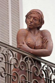 Sculpture by Nicole Brousse, brown woman on balcony railing, brown, standing, balcony railing,