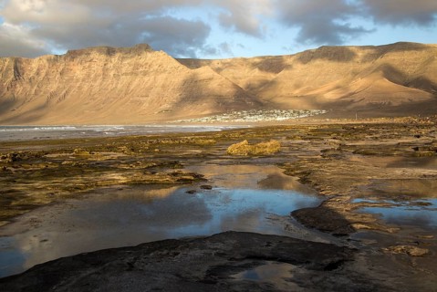 Late afternoon light on beach and cliffs La Caleta de Famara, Lanzarote, Canary islands, Spain,