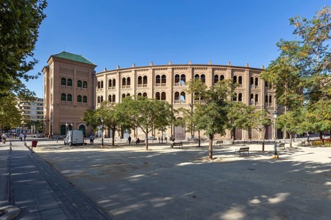 Brick bullring in a sunny setting with trees and clear skies, Granada