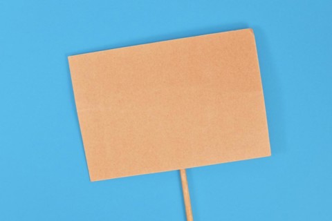 Top view of empty cardboard protest sign on blue background