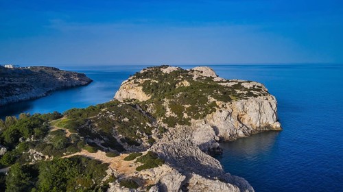 Drone shot, panorama of the rocky coast with steep cliffs, calm sea and a bright blue sky, Anthony