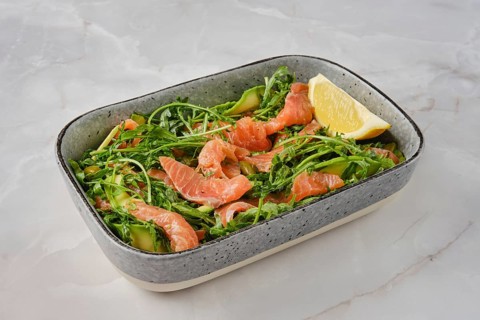 A vibrant salad features fresh smoked salmon slices mixed with crisp arugula and cucumber,