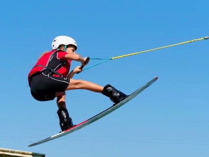 Boy or girl, jump over jump with wakeboard, red life jacket and water sports, water skiing in the