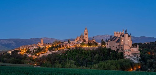 Night scene with an illuminated castle and city in front of dark mountains, a calm and peaceful