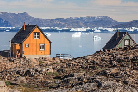 Typical Greenlandic houses in front of icebergs, Inuit settlement, summer, sunny, Uummannaq, West