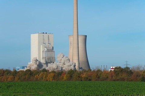 Industrial plant with swirling dust cloud, surrounded by autumnal landscape, blasting of the ash