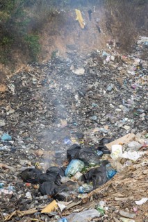 Coking rubbish dump, rubbish pit with waste and plastic rubbish, karst landscape near Vang Vieng,